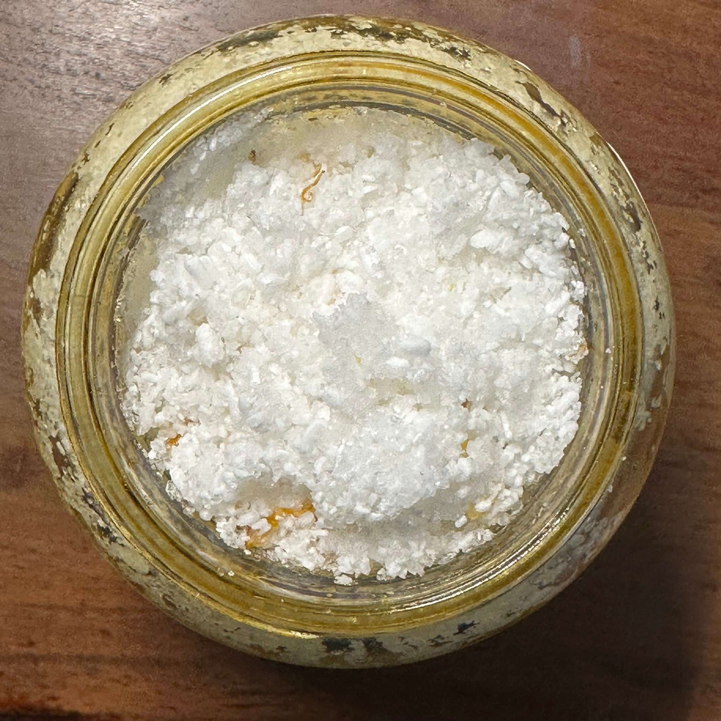 Botanical body scrub in a glass jar, showcasing a natural exfoliant mix of Epsom and sea salts.