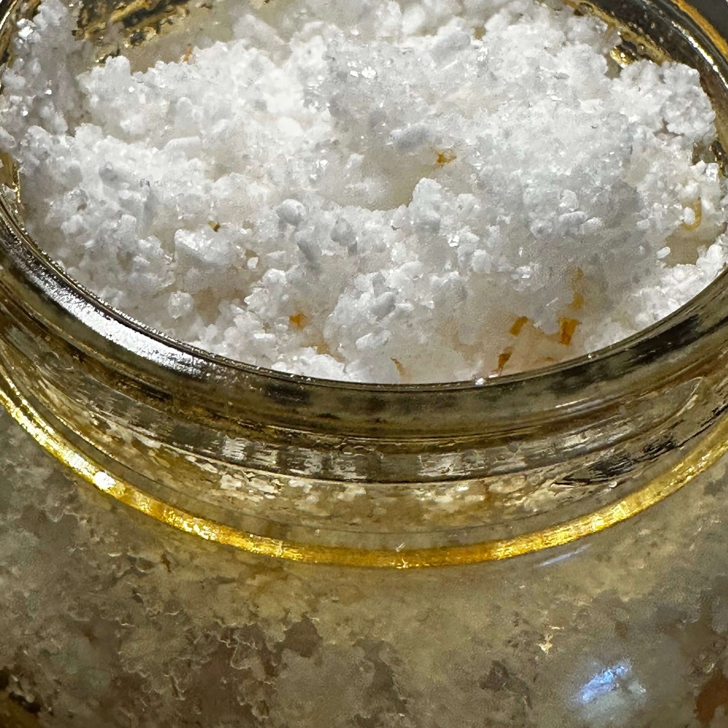 Close-up of a jar filled with white sea salt, showcasing the texture for a botanical body scrub.