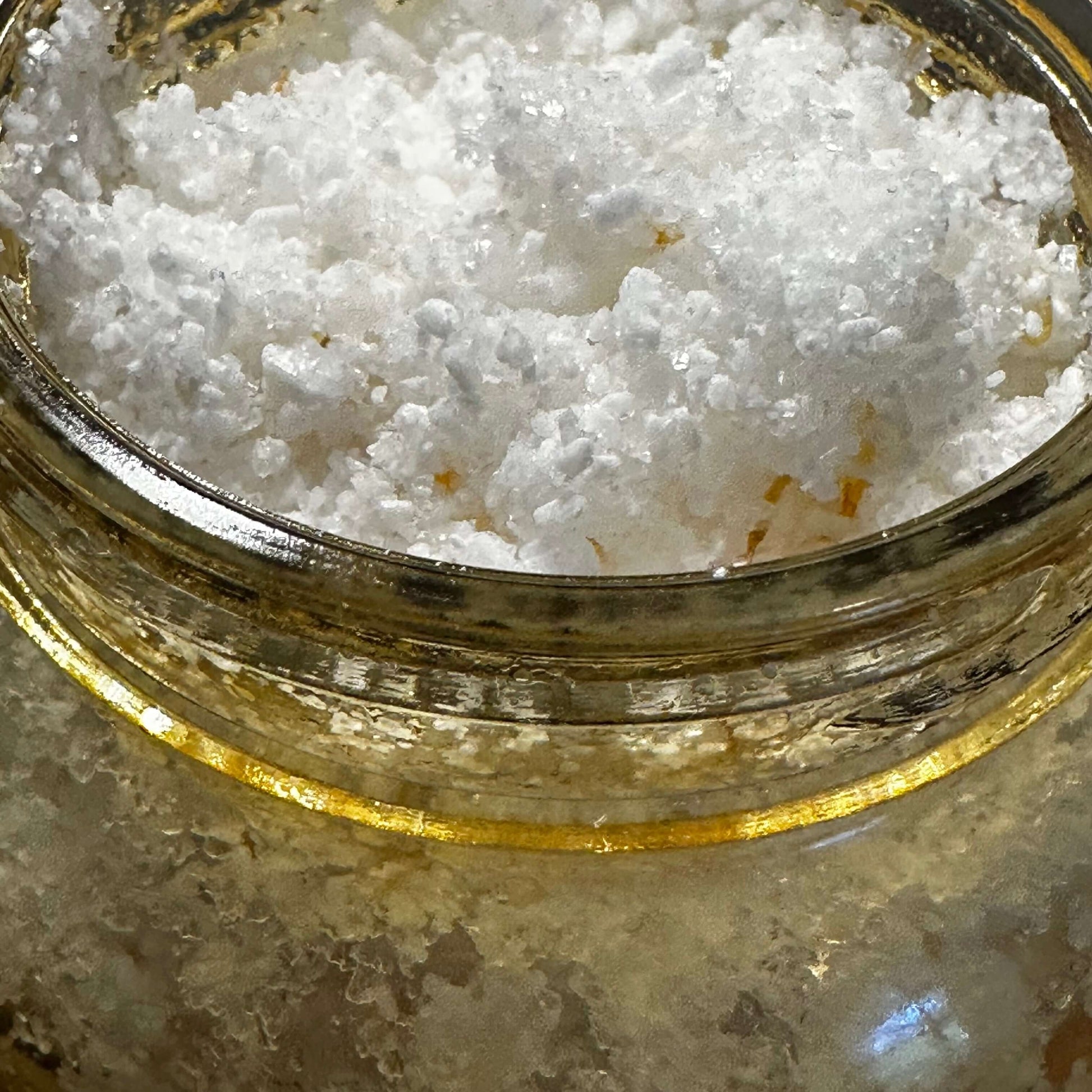 Close-up of a jar filled with white sea salt, showcasing the texture for a botanical body scrub.